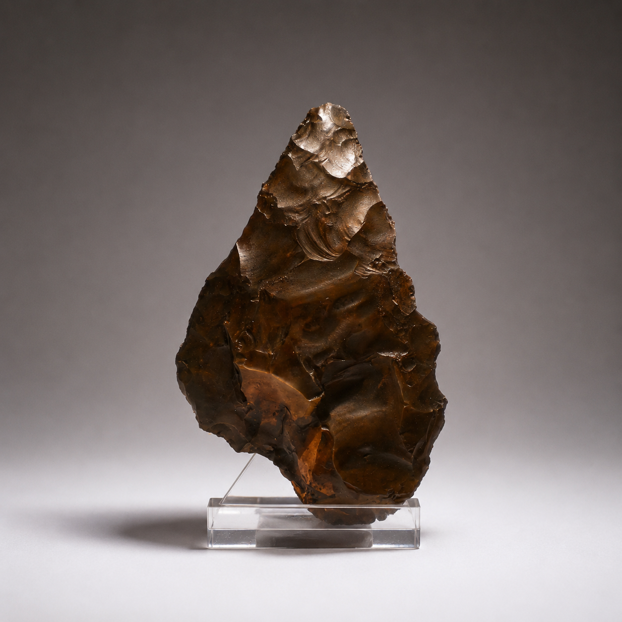 Tallado con silueta de corazón y ápice apuntado. La superficie muestra extracciones profundas de percusión y una pátina ferruginosa de intemperismo saharaui.