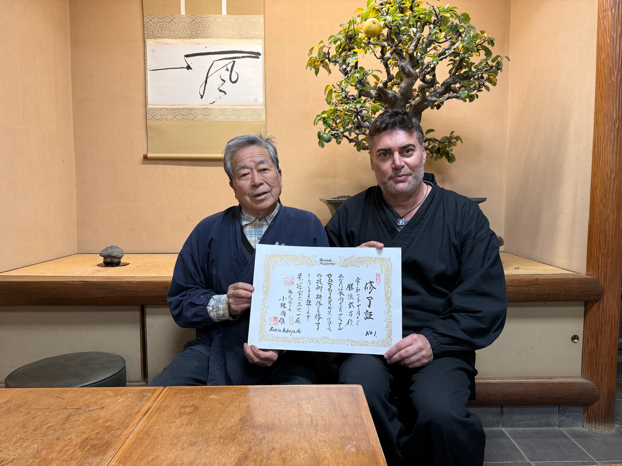Marcial Yuste Blasco y Kobayashi Ippū sosteniendo el diploma Nº1 en el Museo Shunkaen, ante un kakejiku con el carácter 風