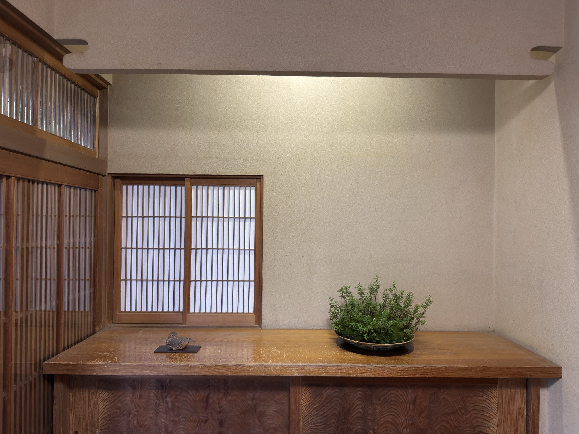 Sekikazari en el recibidor: la talla del pato sobre su ita y un kusamono, sobre un mueble de madera bajo una ventana de shōji